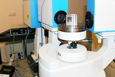 Na widocznym stanowisku pomiarowym znajdują się: goniometr-spektrometr II UV-VIS-IR z wyposażeniem, dwa pryzmaty równoboczne oraz dwa pryzmaty wnękowe do pomiaru współczynnika załamania światła cieczy.